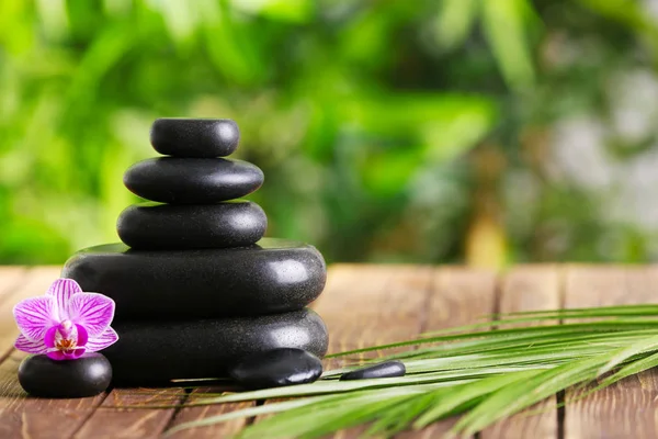 Spa stones with beautiful flower on wooden table outdoors — Stock Photo, Image