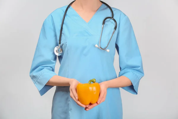 Médico feminino com pimenta fresca no fundo branco — Fotografia de Stock