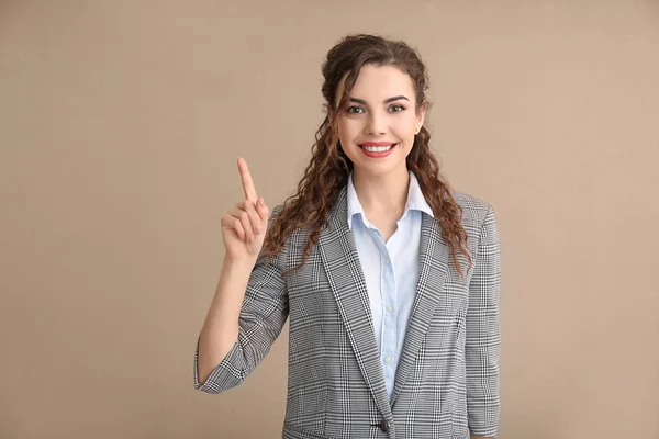 Молода жінка в офіційному одязі з піднятим індексним пальцем на кольоровому фоні — стокове фото