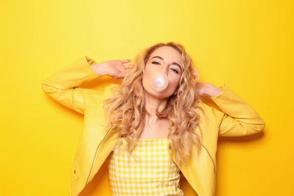 Beautiful young woman with chewing gum on color background — Stock Photo, Image