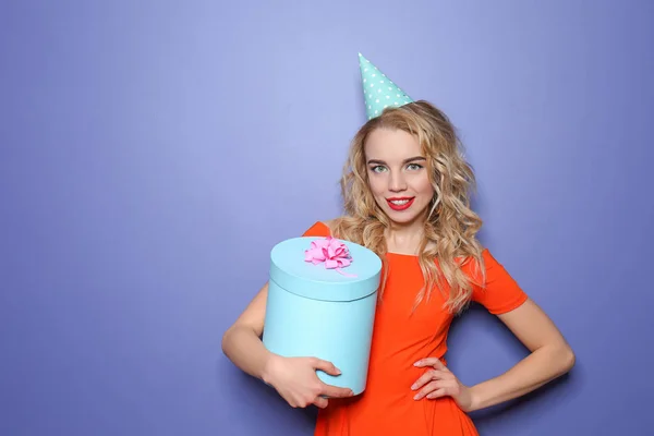 Portrait of beautiful young woman with birthday gift on color background — Stock Photo, Image