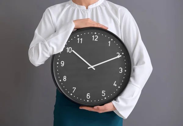 Vrouw met de klok op een grijze achtergrond. Time management concept — Stockfoto