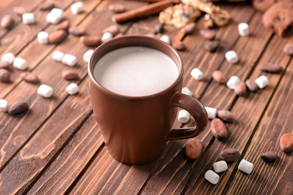 Чашка вкусного какао с зефиром и бобами на деревянном столе — стоковое фото