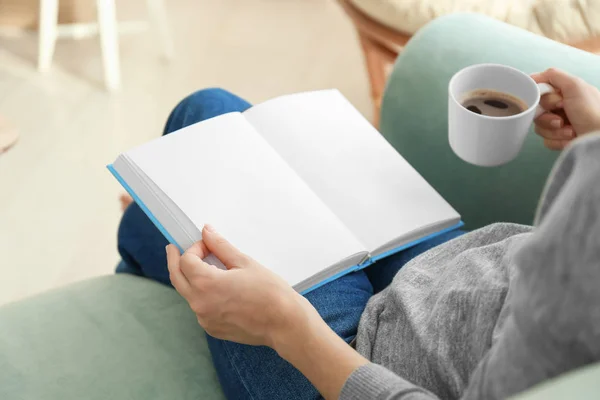 Mujer joven bebiendo café mientras lee libro en casa — Foto de Stock