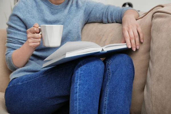 Jeune femme boire du café tout en lisant le livre à la maison — Photo