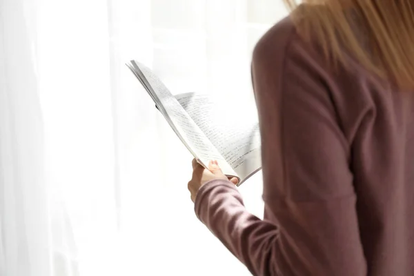 Giovane donna che legge libro interessante a casa — Foto Stock