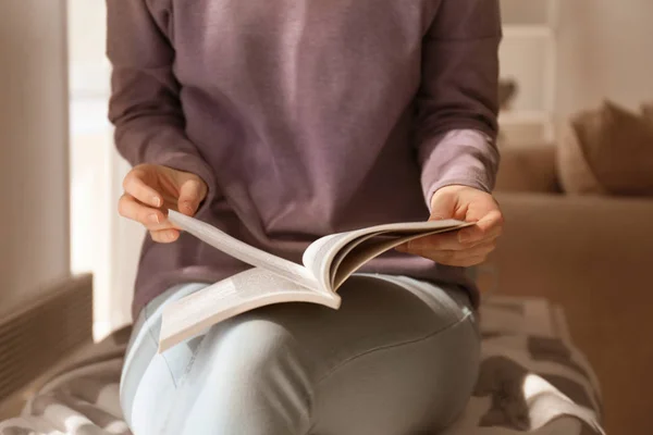 Giovane donna che legge libro interessante a casa — Foto Stock