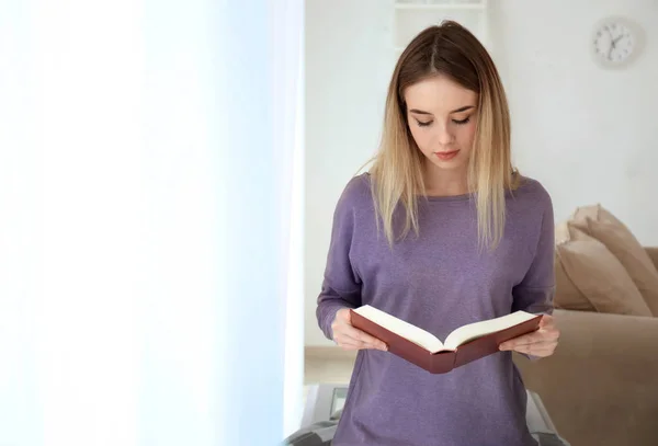 Jovem mulher lendo livro interessante em casa — Fotografia de Stock