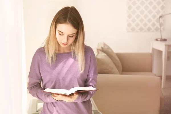 Giovane donna che legge libro interessante a casa — Foto Stock
