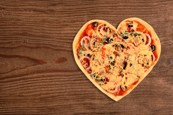 Leckere herzförmige Pizza auf Holzboden — Stockfoto