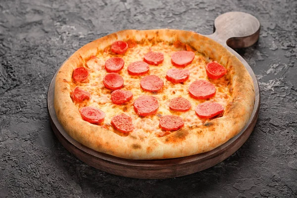 Holzbrett mit leckerer Pizza auf dunkelgrauem Hintergrund — Stockfoto