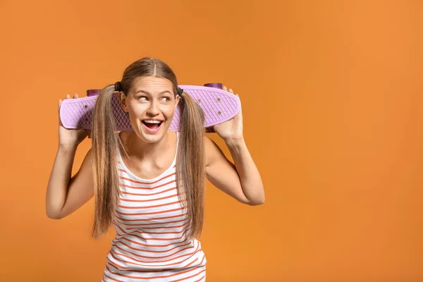 Happy young woman with skateboard on color background — Stock Photo, Image