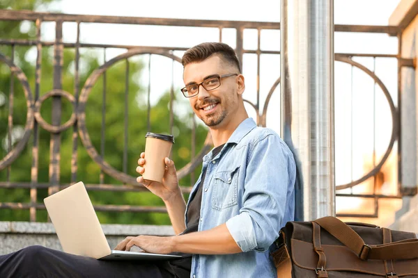 Portrét pohledného podnikatele s laptopem a šálkem kávy venku — Stock fotografie