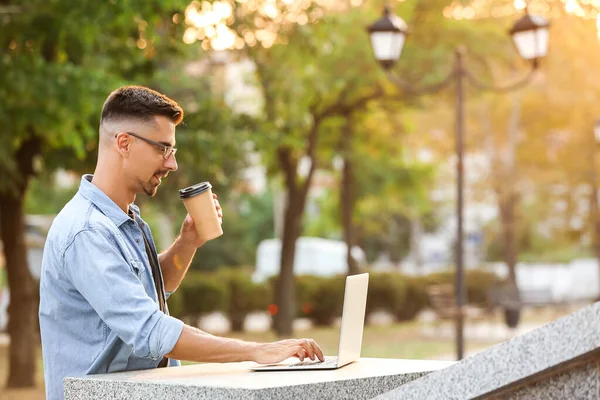 Портрет красивого бизнесмена с ноутбуком и чашкой кофе на открытом воздухе — стоковое фото