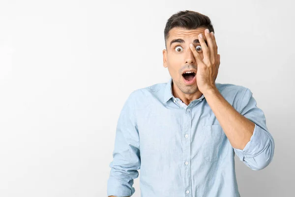 Shocked young man on light background — Stock Photo, Image