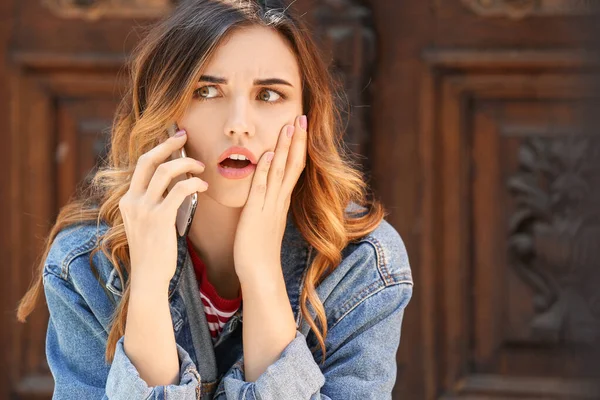 Mujer joven sorprendida hablando por teléfono móvil al aire libre —  Fotos de Stock