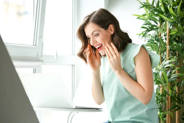 Surprised young woman with laptop at home — Stock Photo, Image