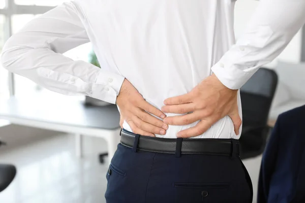 Young man suffering from back pain in office — Stock Photo, Image