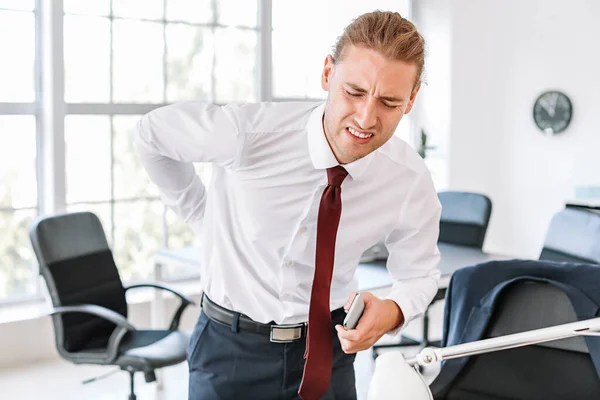 Young man suffering from back pain in office — Stock Photo, Image