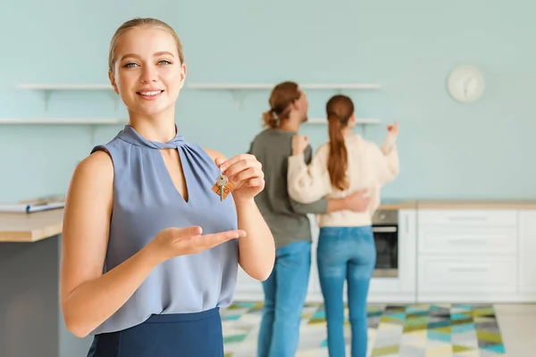 Immobilienmaklerin mit Schlüssel und Kunden im Haus — Stockfoto