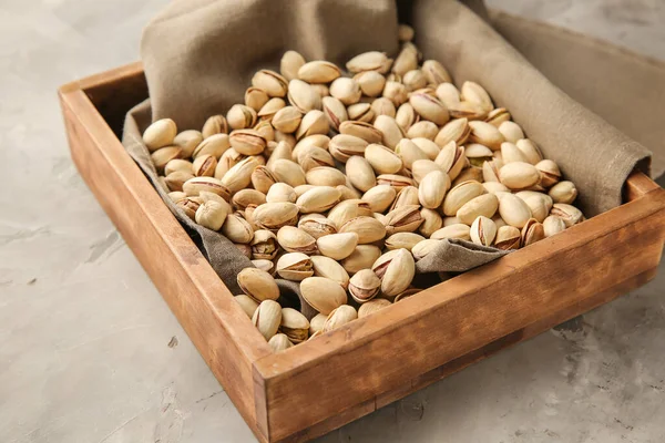 Tray with tasty pistachio nuts on grunge background — Stock Photo, Image