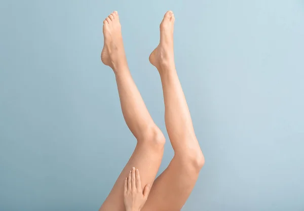 Женщина с красивыми ногами после депиляции на цветном фоне — стоковое фото