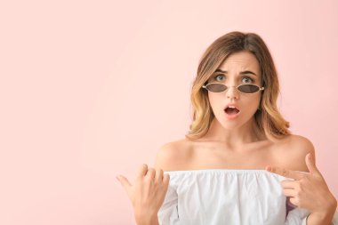 Şaşırmış genç bir kadın, arka plandaki bir şeyi işaret ediyor.