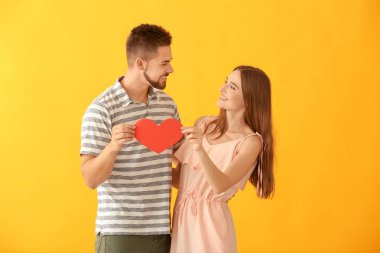 Arka planda kağıt kalpli mutlu genç bir çiftin portresi.
