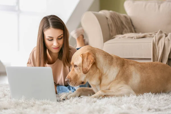 Молодая женщина с симпатичной собакой с ноутбуком дома — стоковое фото