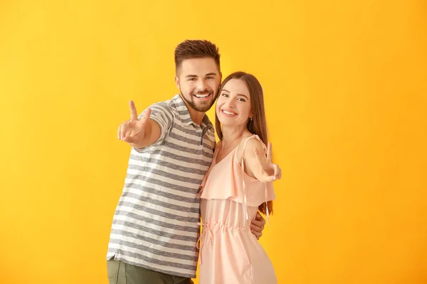 Porträtt av glada unga par visar seger gest på färg bakgrund — Stockfoto