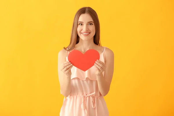 Portrait of happy young woman with paper heart on color background — Stock Photo, Image