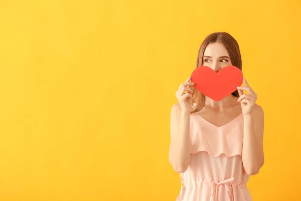 Portrait of happy young woman with paper heart on color background — Stock Photo, Image