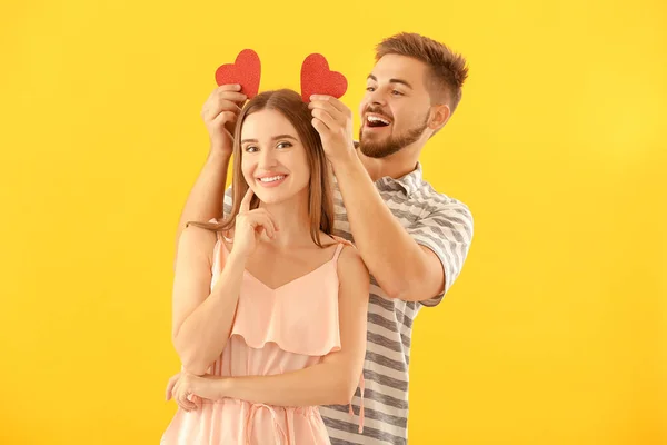 Ritratto di giovane coppia felice con cuori di carta su sfondo a colori — Foto Stock