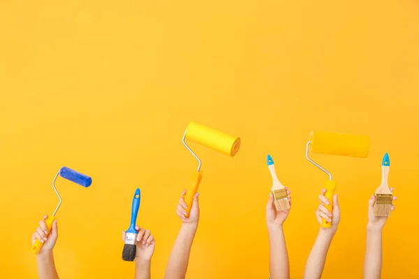 Manos femeninas con herramientas de pintor sobre fondo de color —  Fotos de Stock