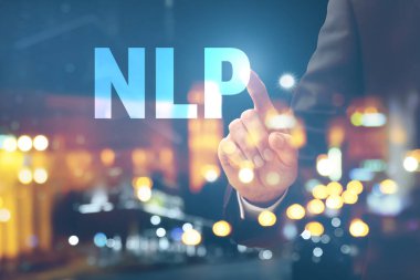 Double exposure of young businessman touching word NLP on virtual screen and illuminated city at night