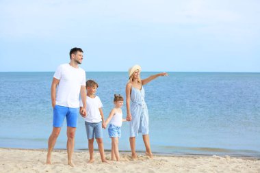 Mutlu bir aile deniz kıyısında yürüyor