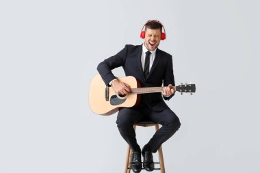 Gitar çalan ve arka planda şarkı söyleyen yakışıklı adam.