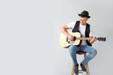 Açık arkaplanda gitar çalan yakışıklı adam.