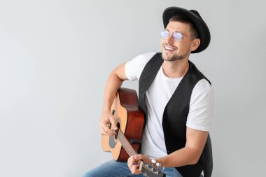 Açık arkaplanda gitar çalan yakışıklı adam.