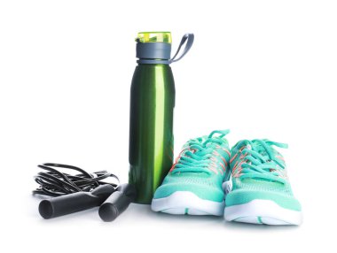 Spor su şişesi, ayakkabılar ve beyaz arka planda atlama ipi.