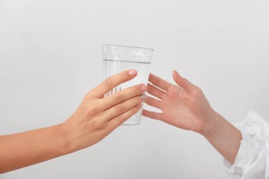 Beyaz arka planda bir bardak su olan kadın eller.
