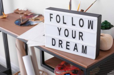 Kapalı alandaki ressamların iş yerlerinde motivasyon cümlesine sahip tahta