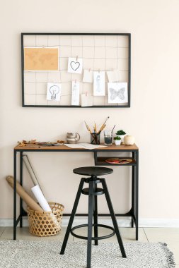 Comfortable workplace with mood board near light wall