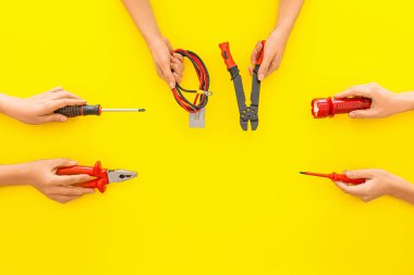 Renkli arka planda elektrikçi aletleri olan kadın eller