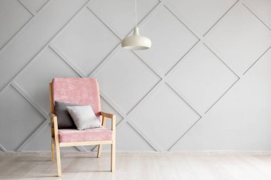 Gri duvarın yanında lambalı şık bir koltuk.