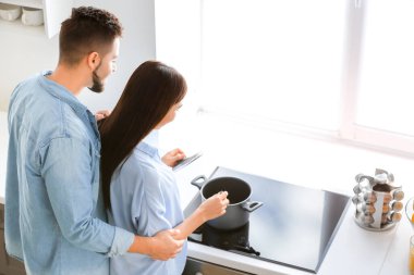 Güzel, genç bir çift mutfakta birlikte yemek pişiriyor.