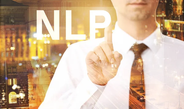 Double exposure of young businessman touching word NLP on virtual screen and illuminated city at night