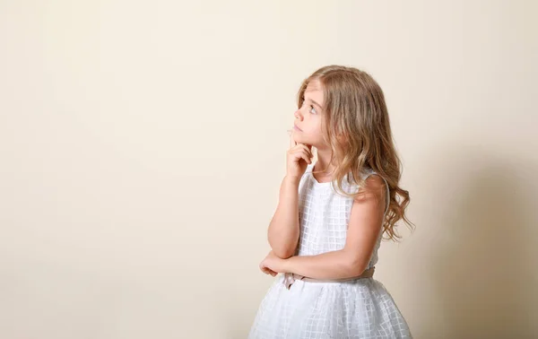 Thinking little girl on light background — Stock Photo, Image