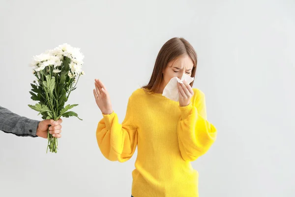 Young woman with allergy refusing to take flowers from man on light background — Stock Photo, Image