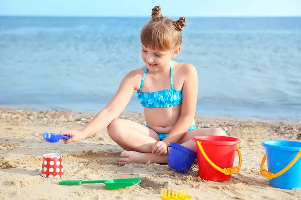 Kleines Mädchen spielt mit Sand am Strand — Stockfoto